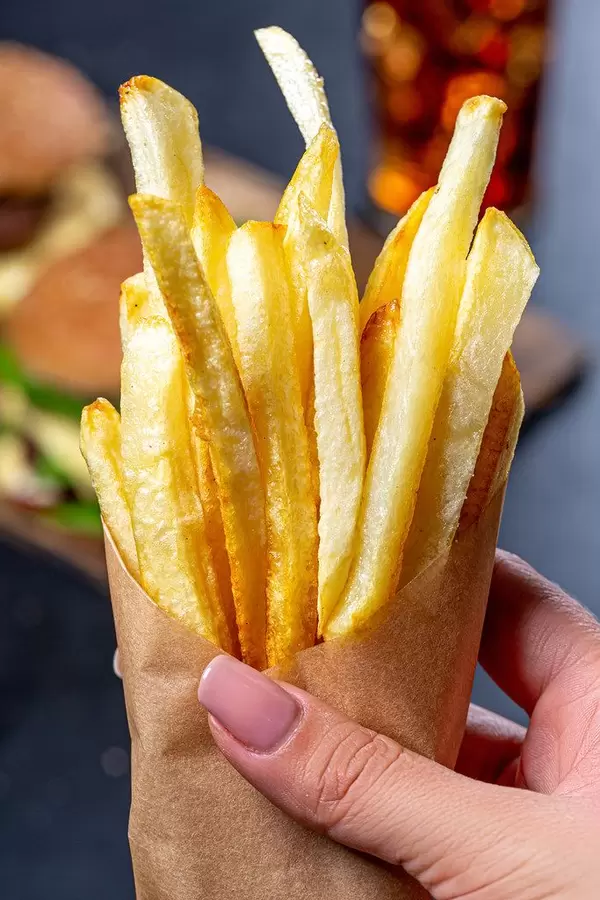 French fries in a paper wrapper in a woman's hand close up (Flip 2019)