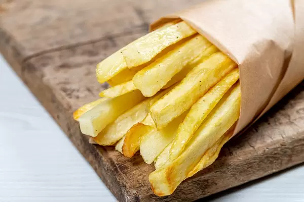 French fries in a paper wrapper on wooden board (Flip 2019)