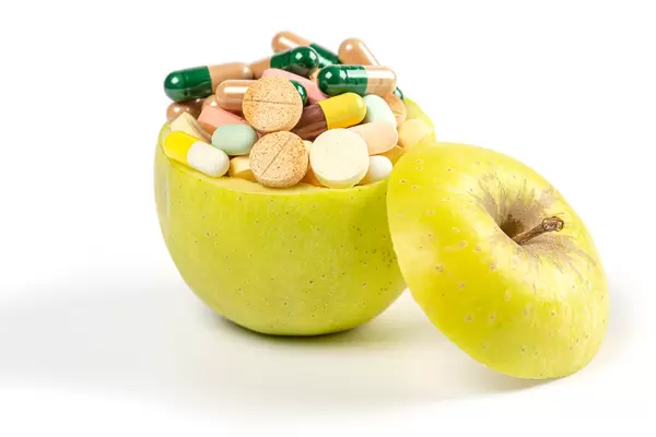 Fresh apple filled with a bunch of medical pills