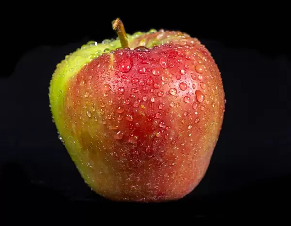 Fresh apple with water drops on black background