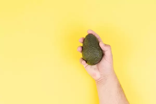 Fresh Avocado in the hand above yellow background