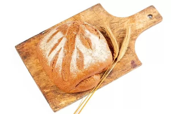 Fresh baked rye bread on wooden kitchen board with spikelets
