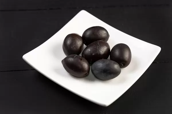 Fresh Black Olives on a White Square Plate on Dark Background
