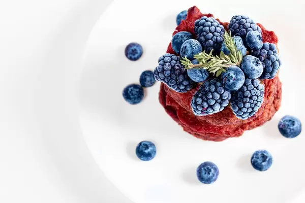 Fresh blueberry and mulberry berries on beet pancakes, top view