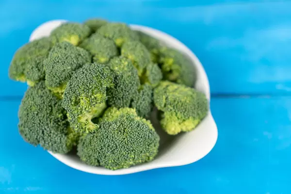 Fresh Broccoli in the bowl above blue wooden table (Flip 2020)