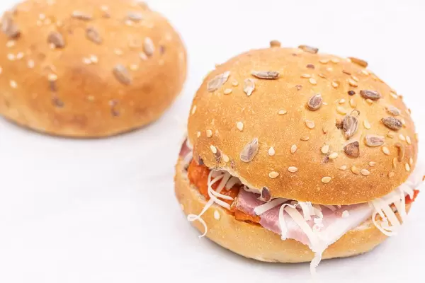 Fresh Buns with Ham Paprika spread and grated Cheese above white background