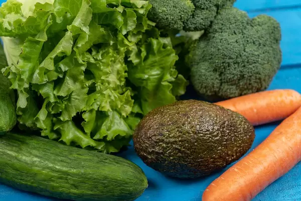 Fresh Carrots, Avocado, Broccoli, Lettuce and Cucumber on the blue boards (Flip 2020)