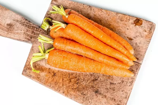 Fresh carrots on a kitchen board, top view