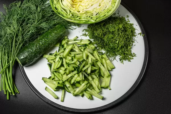 Fresh chopped cabbage, cucumber and dill for cooking salad, dark background