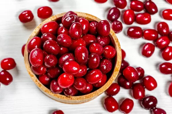 Fresh cornel berries in a wooden bowl. Top view