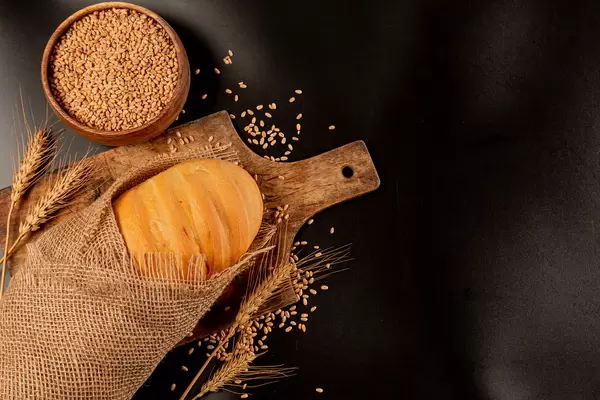 Fresh crispy corn and wheat loaf wrapped in burlap, dark background