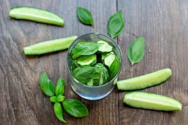 Fresh cucumber slices and Basil leaves on wooden background. The concept of detox cocktail ingredients