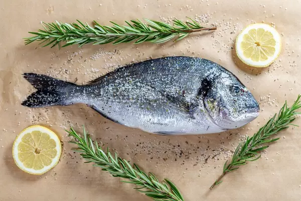 Fresh Dorado fish with lemon slices, spices and fresh rosemary on parchment (Flip 2019)