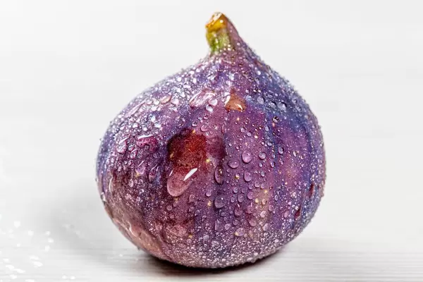 Fresh figs with water drops on white background