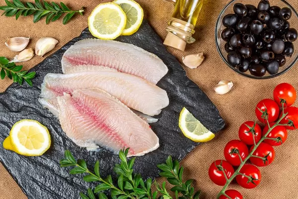 Fresh fish fillet with spices, tomatoes, olives and lemon slices