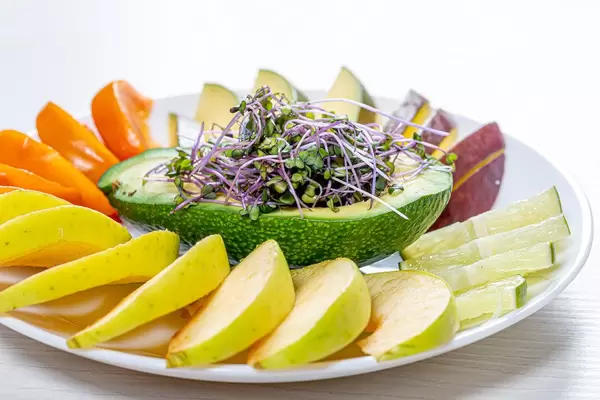 Fresh fruit slicing on a white plate with avocado and micro green cabbage (Flip 2019)
