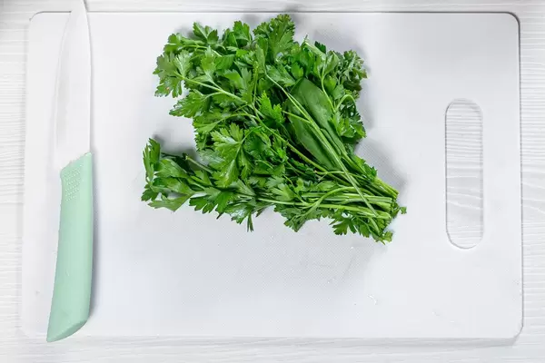 Fresh green parsley with a ceramic knife on a white kitchen Board (Flip 2019)
