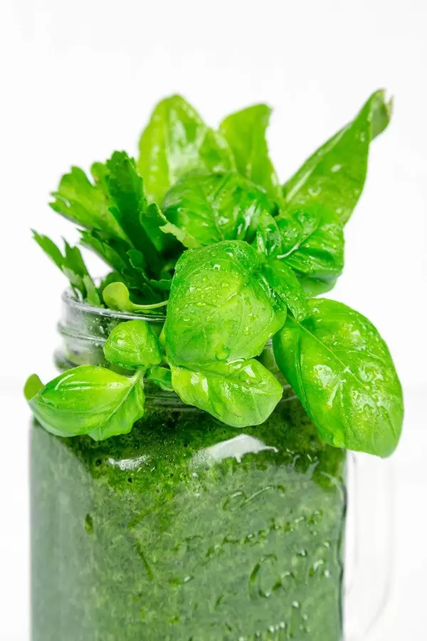 Fresh green smoothie with basil leaves in a glass jar, close-up