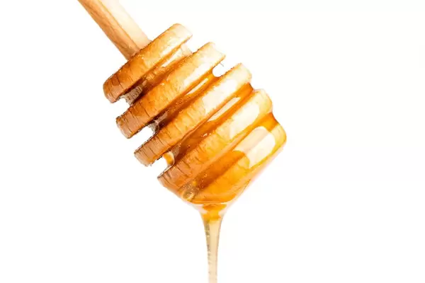 Fresh honey flows down the honey dipper