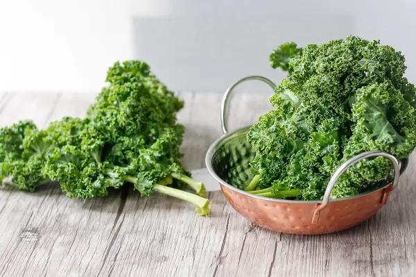Fresh Kale in a copper bowl and on a wooden desk