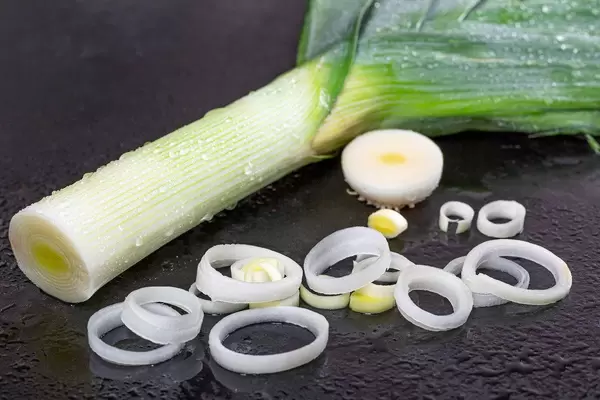 Fresh leeks and pieces on black background