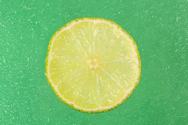 Fresh lime round slice on wet green background