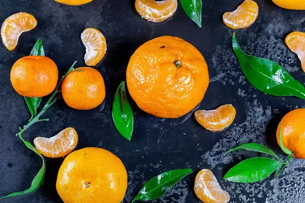 Fresh mandarin oranges fruit with leaves on dark table