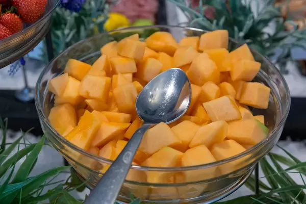 Fresh mango cut in pieces, in a glass bowl with spoon, at the fruit buffet