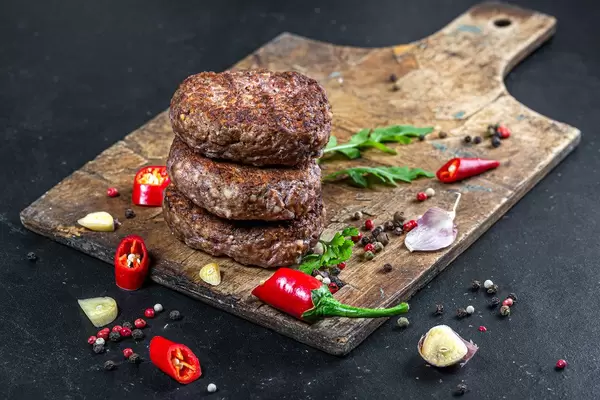 Fresh meat cutlets with spices, pieces of chili and garlic on an old kitchen Board