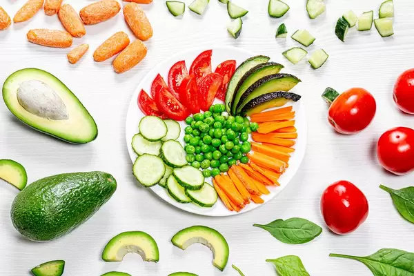 Fresh multicolored sliced vegetables on and around the plate. Top view