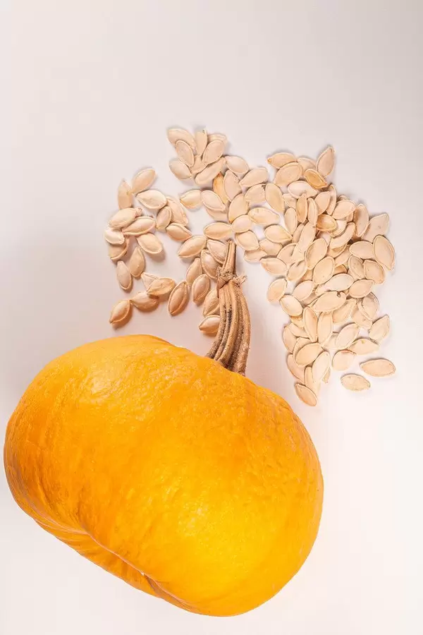 Fresh orange pumpkin and seeds on white background