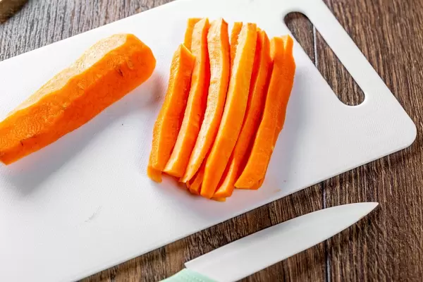 Fresh orange sliced carrots with a knife on the table