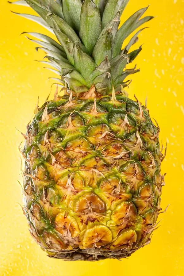 Fresh pineapple on wet yellow background