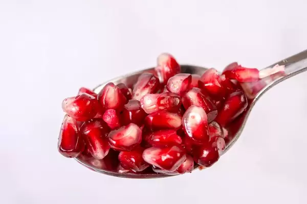 Fresh Pomegranate on the spoon above white background (Flip 2019)