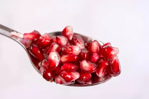 Fresh Pomegranate on the spoon above white background