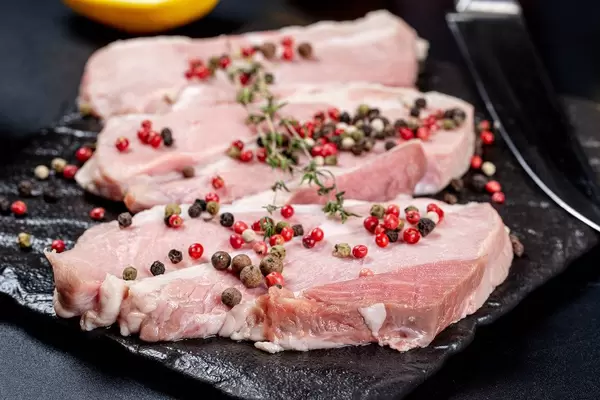 Fresh pork steaks with a mix of peppers peas, close -up