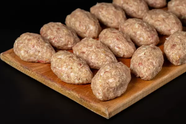 Fresh raw cutlets on kitchen board, dark background