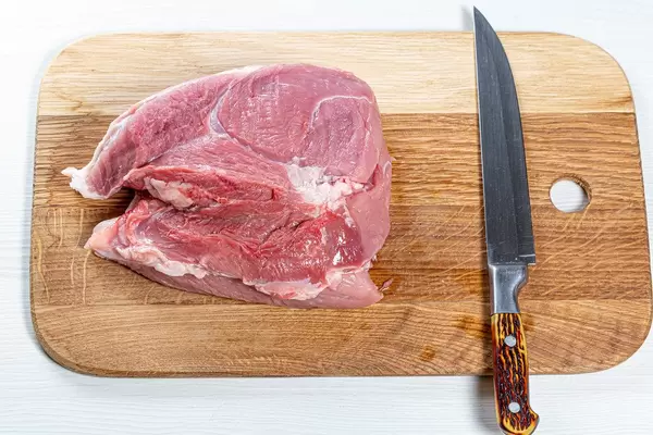 Fresh raw pork meat on kitchen board with knife