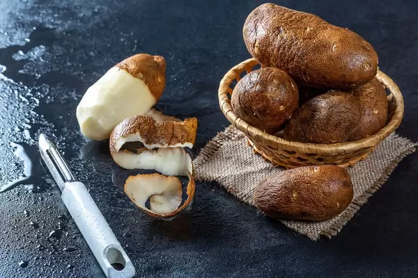 Fresh raw potatoes and potato peeler