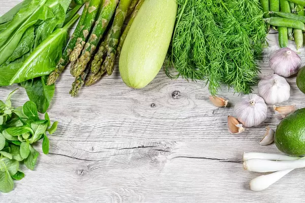 Fresh raw vegetables and greens on a wooden background. Healthy food concep