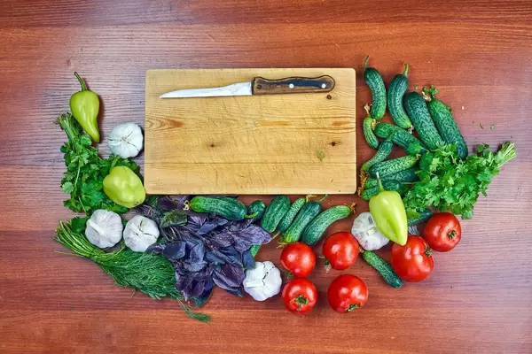 Fresh raw vegetables placed around the wooden cutting board