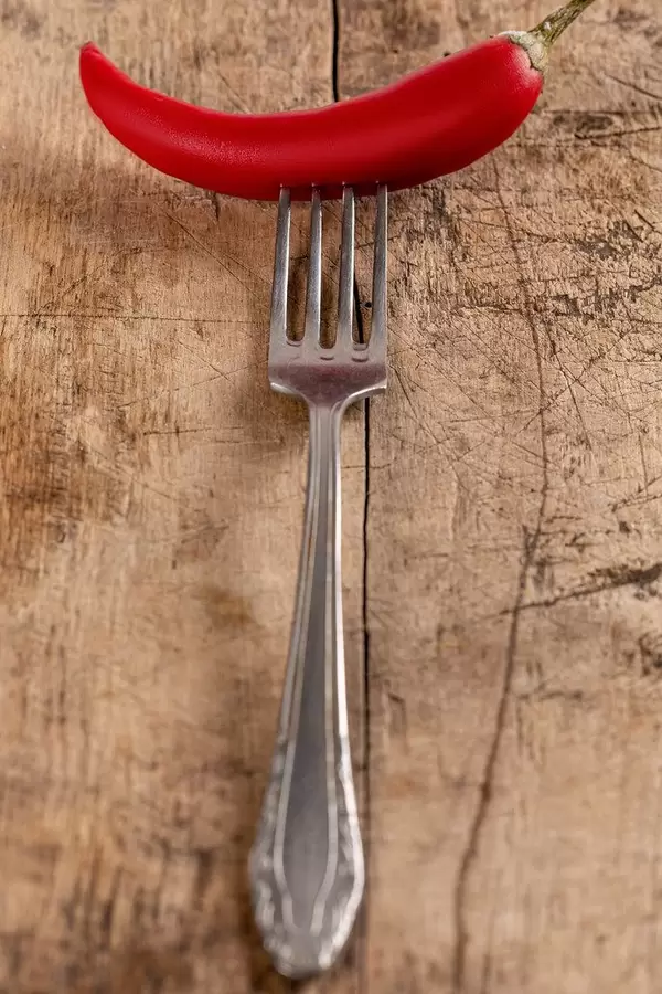 Fresh red chili pepper with fork on old wooden background