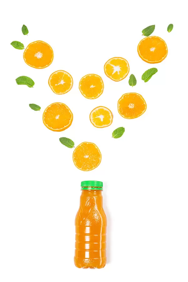 Fresh ripe orange slices and mint leaves on a white background with a bottle of juice