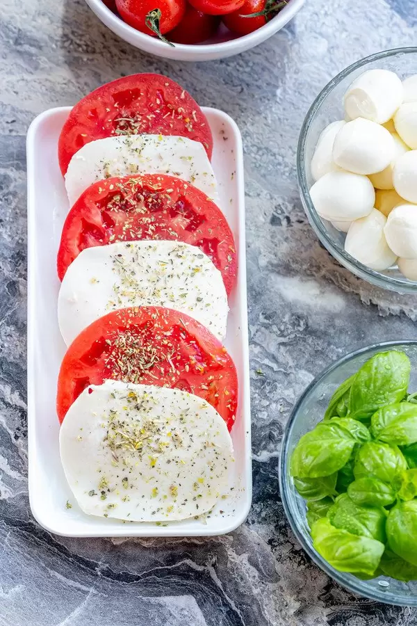 Fresh ripe tomatoes, mozzarella and young green Basil leaves on grey stone background (Flip 2019) (Flip 2019)