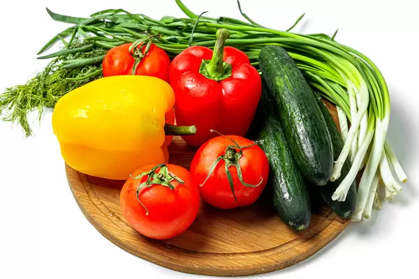 Fresh ripe vegetables and herbs on a wooden kitchen board