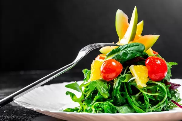 Fresh salad with herbs, tomatoes, avocado and orange on a plate with a fork (Flip 2019)