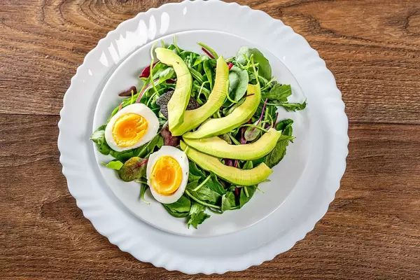 Fresh salad with lettuce, boiled eggs and avocado. Top view