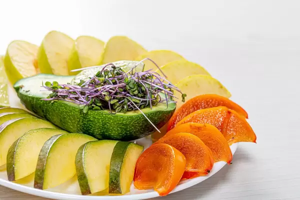 Fresh slices of mango, persimmon, Apple, lime and avocado with micro greens (Flip 2019)