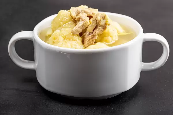 Fresh soup in a white tureen on a black background