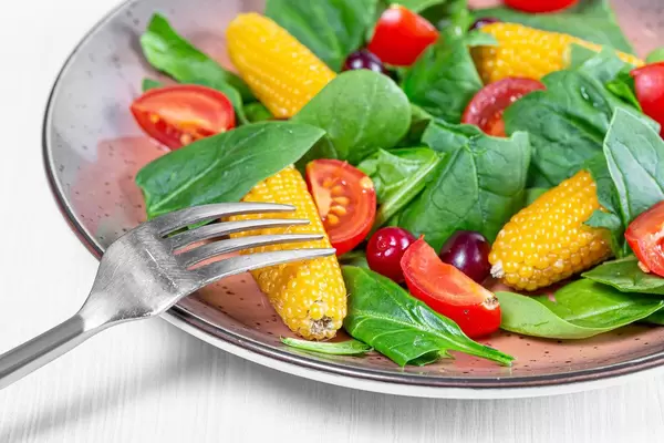 Fresh spinach, tomato slices, dogwood berries and corn. The concept of healthy food